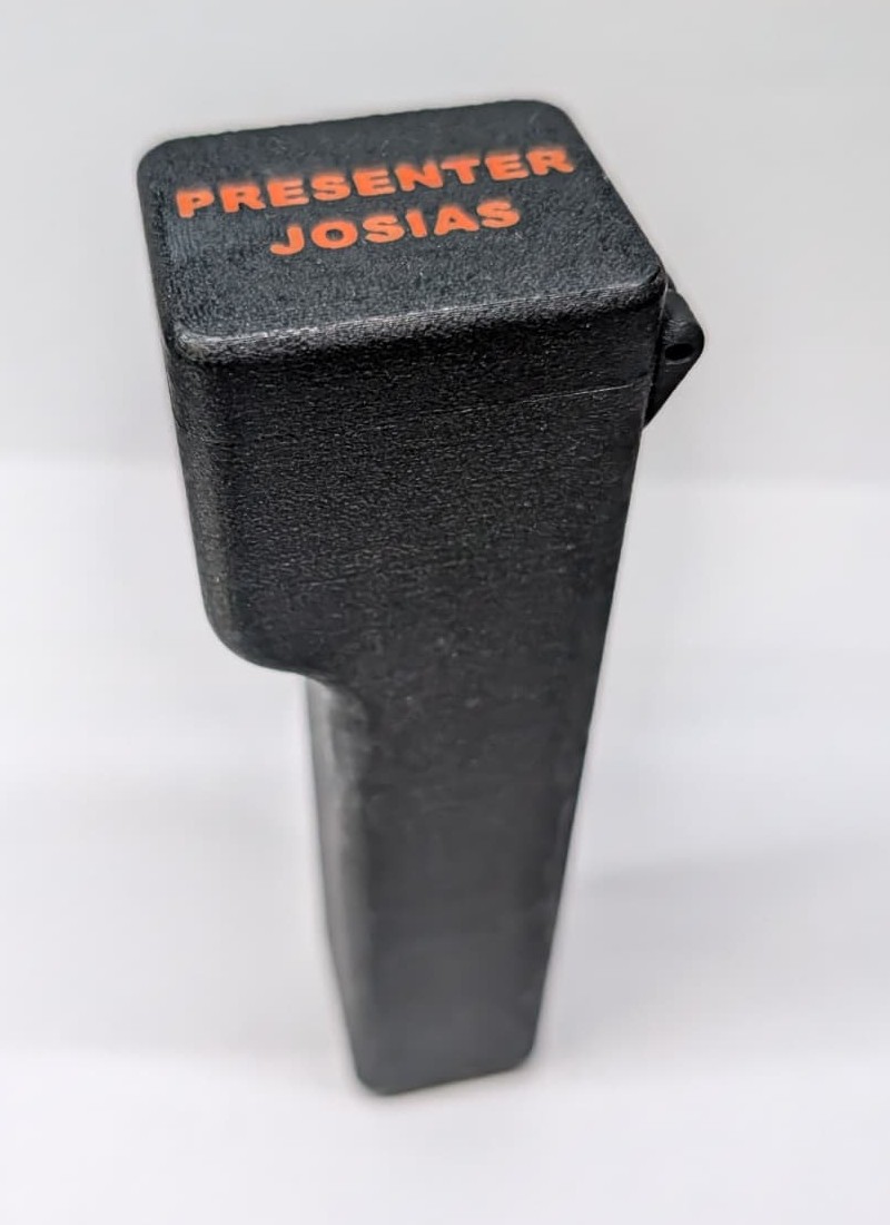 Geschlossenes Case von oben mit der orangen Beschriftung PRESENTER JOSIAS auf dem Deckel